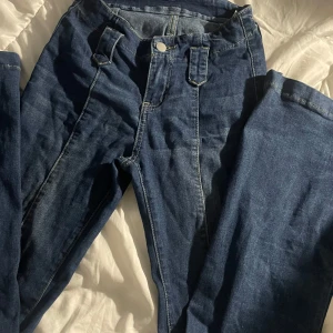 Blå utsvängda jeans från SHEIN - Snygga blå jeans från SHEIN i storlek 26. Modellen har raka ben, klassiska fickor bak och fram, samt breda bälteshällor och kontrastsömmar. Jeansen är tillverkade i jeansmaterial och har en normal passform med knappstängning framtill.