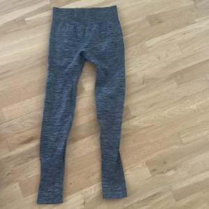 Gråmelerade leggings från Röhnisch - Snygga gråmelerade leggings från Röhnisch med hög midja och tight passform. Tillverkade i ett stretchigt syntetmaterial som andas, perfekta för träning eller chill. Diskret logga på höften och sömlös design för extra komfort.