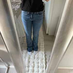 Blå bootcut jeans från Gina tricot  - Snygga blå jeans från Gina tricot i storlek 36. Modellen har klassisk femficksdesign, normal passform över låren och lätt utsvängda ben. Jeansen är i ett mjukt denimtyg och har en tidlös blå tvätt som passar till allt.