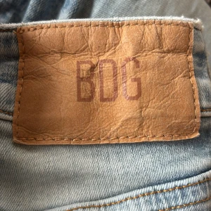 BDG Flare jeans ljusblå W24 L32 - Snygga ljusblå flare jeans från BDG Urban Outfitters. Modellen har klassisk femficksdesign, utsvängda ben och normal midja. Jeansen är tillverkade i bomull och har en cool tvättad look med slitningar för en avslappnad vibe.