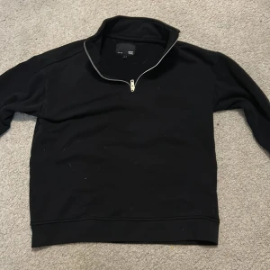 Svart half zip sweatshirt - Svart sweatshirt med half zip-dragkedja och hög krage från 157. Tröjan har en clean look, långa ärmar och är gjord i mjukt bomullsmaterial. Perfekt för lager-på-lager och chill dagar.