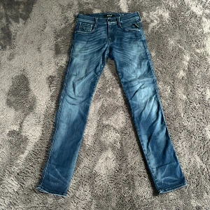 Replay Anbass blå jeans, stl 30/32 - Snygga blå Replay Anbass jeans i storlek 30/32. Jeansen har klassisk femficksdesign, raka ben och tydliga slitningar för en cool look. Tillverkade i mjukt denimtyg med bekväm passform. Perfekta för dig som gillar stilrena och moderna jeans. Hör av er vid frågor!☺️