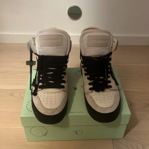 OFF-WHITE HIGH TOP VULCANIZED LEATHER (White,Black) - Hejsan! Säljer ett par exklusiva Off-White Vulcanized High-Top sneakers i vitt och svart Vulcanized läder, storlek EU 40. (Passar även 41-42-43 stor i storleken) Skorna är i nyskick, endast provade/använda en gång. Man ser ytters lite att dem ens är provade. Alla originaltillbehör följer självklart med. Allt riktigt. Bevis finns.  Detta är ett par tidlösa och stilrena sneakers som kombinerar hög kvalitet med Off-Whites unika design. Perfekt för dig som söker ett par exklusiva skor. 