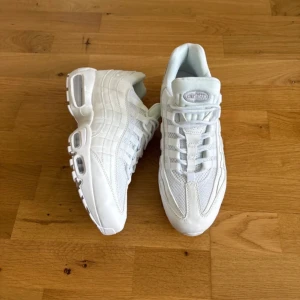 Nike Air Max 95 Triple White - Nike Air Max 95 i helvitt med snygga detaljer och klassisk chunky sula. Ovandelen är i mesh och syntet med skinnpaneler och synliga Air-enheter i sulan. Perfekt för dig som gillar stilrena sneakers med sportig vibe och maxad komfort.