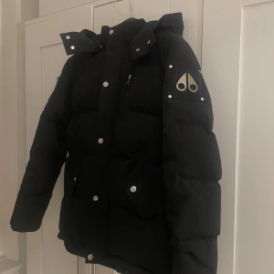 Moose knuckles pufferjacka - Säljer en svart pufferjacka från Moose Knuckles. Nu när de kyliga dagarna väntar oss så är den bästa investeringen för dig att satsa på en jacka som håller dig varm och stilig. Jackan är storlek XL för barn alltså passar den allt från 168-173 cm.  Säljer då den tyvärr inte längre passar mig. Hör gärna av dig vid några frågor.