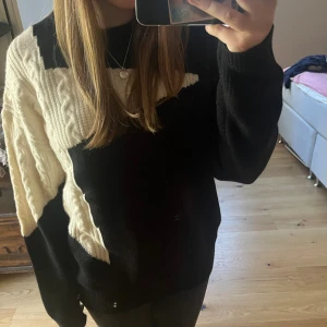 Svart stickad tröja med vit stjärna - Säljer en svart stickad tröja från Aelfreic Eden med en stor vit stjärna över axeln och ena ärmen. Tröjan har rund halsringning och långa ärmar. oversized