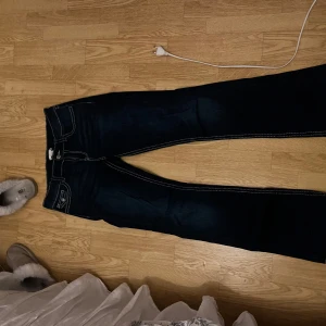 Mörkblå bootcut jeans Gina Tricot - Snygga mörkblå jeans från Gina Tricot med kontrasterande vita sömmar och klassiska fickor både fram och bak. Modellen har bootcut-ben och är tillverkad i mjukt denimtyg som sitter skönt hela dagen.