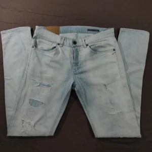 Ljusblå slitna jeans från Dondup - Ljusblå jeans från Dondup med snygga slitningar och hål på låren. Klassisk femficksmodell med raka ben och gylf med knappar. Jeansen har ljus tvätt och coola detaljer på bakfickorna. Perfekta för en avslappnad streetstil.  Extra grej, ganska slim storlek.