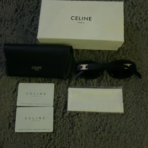 Svarta solglasögon från Celine - Snygga svarta solglasögon från Celine med ikoniska silvriga detaljer på sidorna. Modellen har en klassisk, lite kantig form och är tillverkad i Italien. Kommer med originalfodral, putsduk och äkthetskort. Perfekt accessoar för att lyfta din stil.