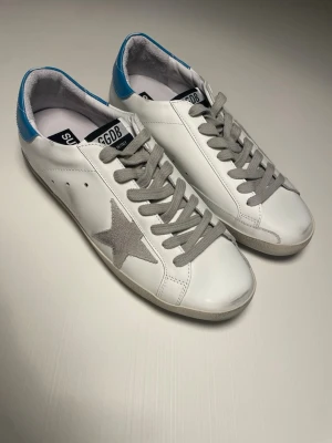 Golden Goose Skor - Snygga sneakers från Golden Goose med den ikoniska beiga stjärnan. Skorna är i bra skick och kommer med dustbag. Modellen heter Superstar och skorna är storlek 42. Pris kan diskuteras 🤝 Skriv ifall ni har fler frågor 💯