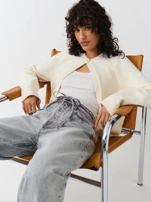 Krämvit kofta från Gina Tricot - Säljer en krämvit kofta från Gina Tricot med rund halsringning och en enkel knapp framtill. Koftan är stickad, har lång ärm och en clean, minimalistisk look som är lätt att styla till olika outfits. Ej några defekter men väl använd!