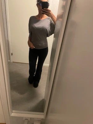 Grå loose topp med trekvartsärm - Säljer en grå loose-fit topp med trekvartsärm och rund halsringning. Toppen har en avslappnad passform och är tillverkad i ett mjukt material som känns skönt mot huden. Perfekt att styla med jeans eller kjol för en chill look.