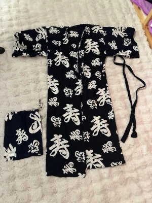 Yasuragi kimono  - Säljer en Yasuragi morgonrock/ kimono tillverkad i mjuk bomull. Kimonon har breda ärmar, knytband i midjan och kommer med en matchande tygpåse. Perfekt för dig som vill ha något unikt och bekvämt. Passar M och L i storlek 