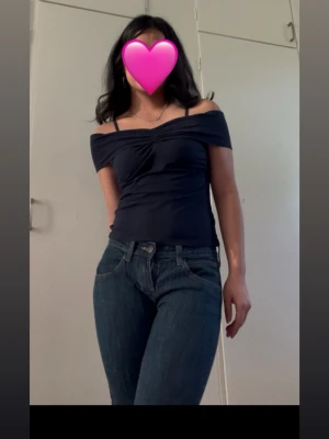 Mörkblå offshoulder topp - Snygg mörkblå offshoulder topp med smickrande rynkdetalj framtill. Toppen är tight och har korta ärmar som sitter snyggt över axlarna. Perfekt att styla med jeans eller kjol för en trendig look.