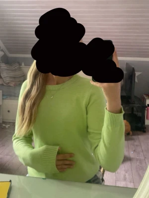 Ljusgrön stickad tröja - Säljer en ljusgrön stickad tröja med rund hals och långa ärmar. Tröjan har ribbade muddar vid ärmslut och nederkant, vilket ger en snygg och enkel look. Perfekt att matcha med jeans eller kjol för en fräsch stil.