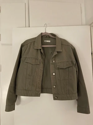 grön  jeansjacka från g perfect jeans - Säljer en grön  jeansjacka från g perfect jeans i storlek L. Jackan har klassisk krage, två bröstfickor med lock och knappar framtill. Croppad modell med raka ärmar och enkel, clean look. Perfekt till vår och höst.