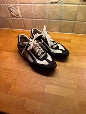 Svarta och vita sneakers från Dsquared2 - Säljer ett par stilrena sneakers från Dsquared2 i svart och vitt. Skorna har snörning, detaljer i mocka och skinn samt Dsquared2-logga både på plösen och hälen. Snygg kontrast mellan svart och vitt, med klassisk rund tå och platt sula.