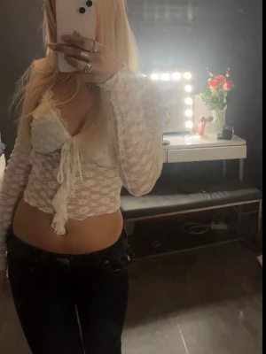 Vit spetsblus med knyt och volang - Säljer en vit, croppad spetsblus med långa ärmar och v-ringning. Toppen är använd kanske 2 gånger 