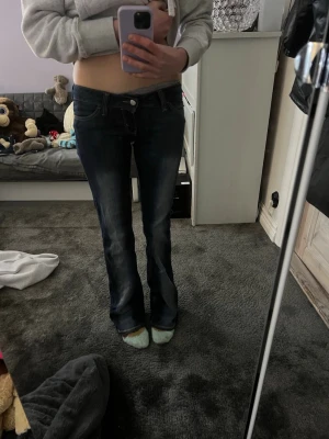 Cheap Monday bootcut jeans  - Säljer ett par mörkblå bootcut jeans från Cheap Monday med låg midja och snygga slitningar. Klassisk femficksmodell med vit patch och logga bak. Jeansen är i stretchigt denim och har kontrastsömmar för extra detalj.  Dom är aldrig andvända och är o längd 34❤️❤️