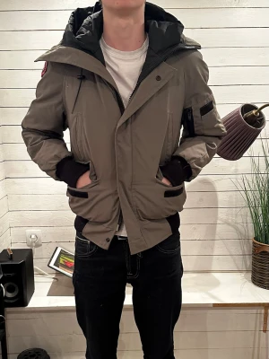 Grå dunjacka från Canada Goose - Säljer en grön/grå Canada Goose dunjacka som är väldigt varm. Passar 170! Skriv för funderingar!