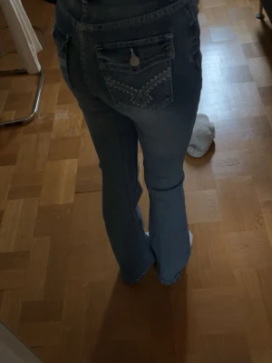 Blå bootcut jeans med broderade fickor -  blå jeans med bootcut passform och broderade detaljer på bakfickorna. 