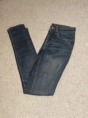 Tiger of Sweden jeans blå - Mörkblå jeans från Tiger of Sweden med klassisk femficksdesign och snygga kontrastsömmar. Jeansen har en smal passform och är tillverkade i mjukt denimtyg som sitter tajt längs benen. Perfekta för dig som gillar en stilren och modern look.