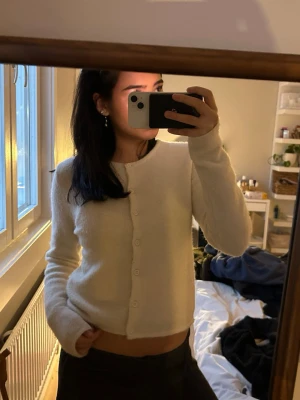 Vit kofta från Gina tricot  - Supermjuk och fluffig vit kofta från Gina tricot med rund halsringning och knappar hela vägen framtill. Långärmad och lite croppad modell som är perfekt att slänga över ett linne eller t-shirt. Materialet känns lyxigt och mysigt.