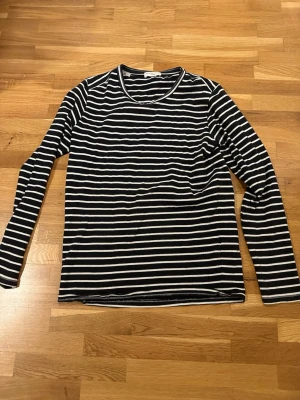 Randig långärmad tröja Selected Homme - Säljer en svart och vit långärmad tröja från Selected Homme, modell indigo. Tröjan har klassiska horisontella ränder och rund halsringning. Perfekt för dig som gillar en enkel men stilren look.