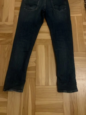Replay Wallys mörkblå jeans - Mörkblå jeans från Replay, modell Wallys, med klassisk femficksdesign och snygga slitningar. Jeansen har raka ben och normal passform, tillverkade i slitstarkt denimtyg. Märkespatch bak i midjan och detaljerade sömmar på bakfickorna.