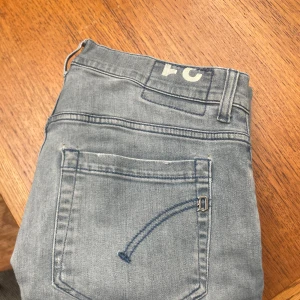 Dondup George - Säljer ett par ljusblå skinny fit jeans från Domdup i storlek 31. Jeansen har klassisk femficksdesig, snygga slitningar och är tillverkade i en stretchig bomullsblandning för extra komfort. Perfekta för dig som gillar en smal siluett och avslappnad look!