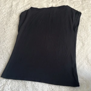 Svart t-shirt från 157, storlek M - Svart t-shirt från 157 i storlek M. Enkel och stilren design med rund hals och korta ärmar. Tillverkad i mjuk bomull som känns skön mot huden. Perfekt för dig som gillar minimalistiska plagg och vill ha en klassisk svart tee i garderoben.