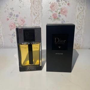 Dior Homme Intense EdP 100ml - Dior Homme Intense Eau de Parfum 100ml med elegant svart och transparent glasflaska. Parfymen har en lyxig känsla med sin mörka, stilrena design och tillhörande svart kartong. Klassisk och maskulin doft från Dior, perfekt för dig som gillar exklusiva parfymer.
