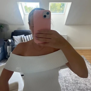 Vit ribbad offshoulder topp - Supersnygg vit ribbad topp med offshoulder-modell. Toppen har en bred, vikt kant över axlarna och sitter figurnära. Knappt använd och i väldigt bra skick. 