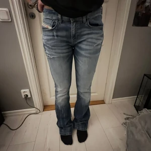 Lågmidjade Diesel Jeans - Säljer ett par blå bootcut jeans från Diesel med snygga slitningar, i storlek 16y men i referens passar de storlek 38/40🌟Pris kan diskuteras!! 