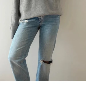 Ljusblå ripped jeans från H&M, strl 34 - Ljusblå jeans från H&M. Snygga slitningar och hål på knät ger en cool, avslappnad vibe. Klassisk femficksdesign och tillverkade i bomull. 