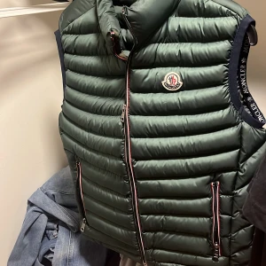 Grön dunväst från Moncler - Snygg grön dunväst från moncler. Västen har två fickor med dragkedja och hög krage.  Skriv vid frågor!
