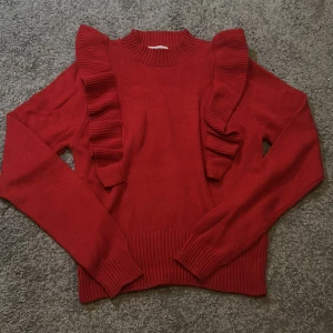 Stickad tröja röd - Stickad röd tröja med fina volanger. Köpte denna för att ha på julafton. ❤️Sedan dess har den ej rörts. Inga skavanker alls. Som ny.