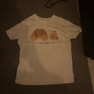 Palm Angels vit t-shirt med björntryck - Vit t-shirt från Palm Angels med en björn på magen. Bra skick andvänd en två gånger. Pris ej hugget i sten