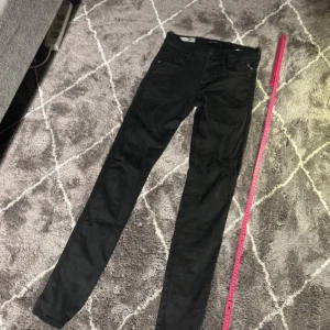 Svarta Replay Anbass jeans herr - Säljer ett par svarta Replay Anbass jeans i klassisk femficksmodell. Jeansen har slim passform, normal midja och raka ben. Materialet är mjukt och stretchigt för extra komfort. Perfekta för dig som gillar stilrena och snygga jeans med diskret logga på fickan.riktigt riktigt små i storlekarna.