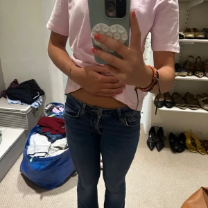 Blå lågmidjade bootcut jeans - Säljer ett par blå jeans med låg midja och bootcut-snitt. Jeansen har klassiska fem fickor och sitter tajt över låren men släpper ut lite vid bensluten. Perfekta för dig som gillar en retro vibe och vill ha ett par snygga jeans till vardags.