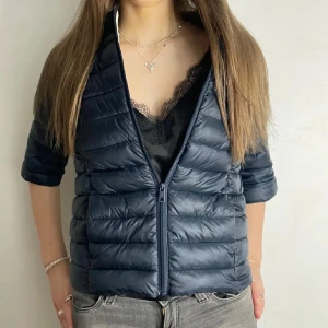 Mörkblå dunjacka med dragkedja - Snygg mörkblå dunjacka med quiltad design och dragkedja framtill. Jackan har en trekvartsärm, perfekt för lager-på-lager-stil. Köpt här på plick. Använd en höst.