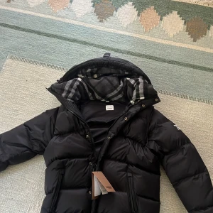 Burberry pufferjacka - Jackan är aldrig använd och har kvar tags väldigt bekväm och varm och passar perfekt nu inför hösten och vintern. Armarna är avtagsbara storleken på jacka är xl men skulle säga att det är en blandning mellan L och XL 