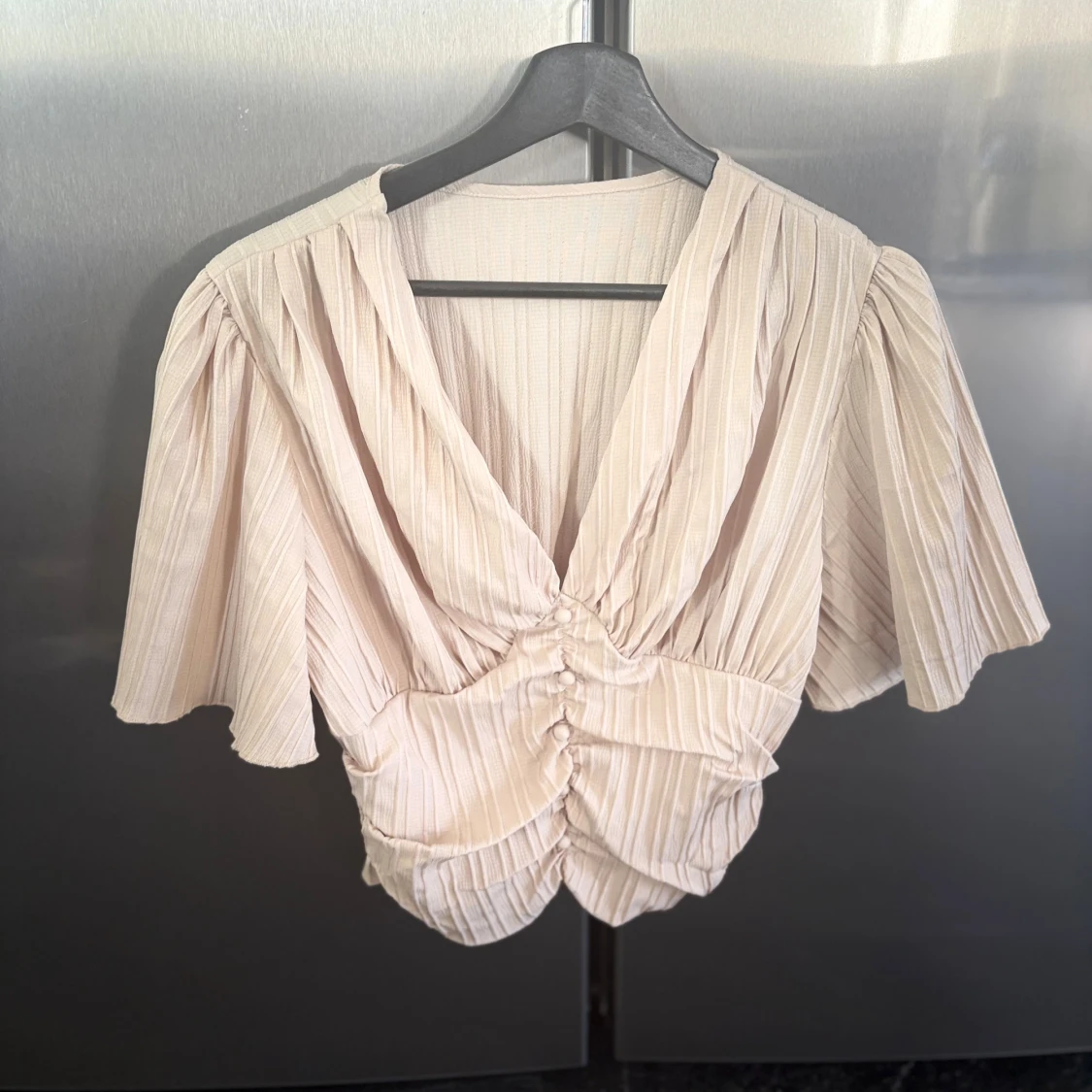 Beige blus med knappar och volang