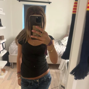 Svart tight topp med v-ringning - En svart, tight topp med korta ärmar och snygg v-ringning. Enkel och stilren design som passar perfekt till jeans eller kjol. Mjuk och stretchig bomullskänsla som sitter skönt på kroppen.