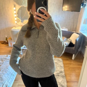 Grå stickad half zip-tröja Object - Supermysig grå stickad tröja från Object med ribbad struktur och half zip-dragkedja. Hög krage och långärmad modell, perfekt för kyliga dagar. Snygg och enkel att styla till både jeans och leggings.