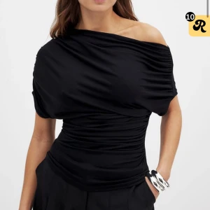 Svart offshoulder topp med drapering - Snygg svart topp med offshoulder-design och draperad effekt över hela plagget. Toppens passform är tight och den har korta ärmar. Perfekt för dig som vill sticka ut med en stilren och trendig look. Den är helt ny med lappar kvar storlek 34-36 från nakd 🥰nypris 349