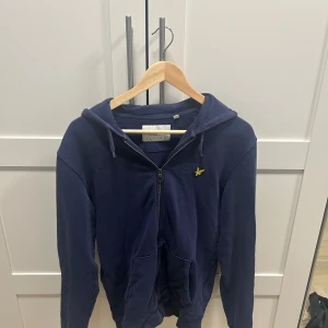 Marinblå hoodie från Lyle & Scott - Säljer en marinblå hoodie från Lyle & Scott. Tröjan är lite använd och i bra skick. 