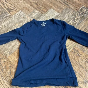 Mörkblå långärmad tröja H&M - En basic mörkblå långärmad tröja från H&M i mjuk bomull. Perfekt att ha som lager eller bara som den är. Enkel och stilren design utan tryck eller mönster, med rund hals och normal passform.
