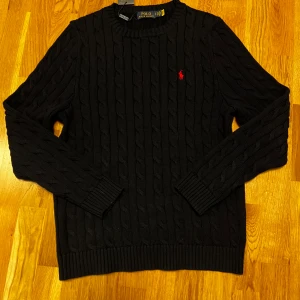 Marinblå kabelstickad tröja Polo Ralph Lauren - Kabelstickad marinblå tröja från Polo Ralph Lauren storlek S men passar mer M Perfekt för dig som gillar stilren och tidlös design.