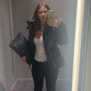 Svart Moncler dunjacka med päls - Säljer en svart glansig dunjacka från Moncler med fluffig päls på huvan. Jackan har dragkedja framtill, två sidofickor med dragkedja och snygga quiltade detaljer. Perfekt för dig som vill ha en varm och stilren look under vintern.